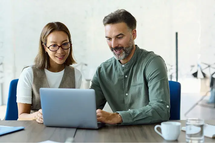 Two colleagues reviewing benefits information on a laptop