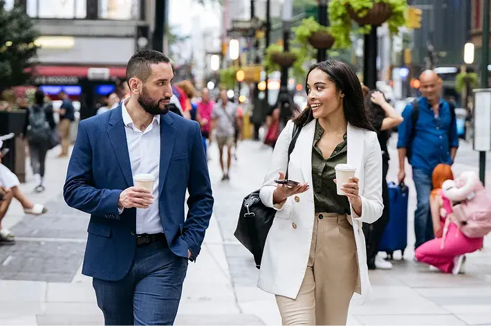 Two professionals walking and talking on a busy city street